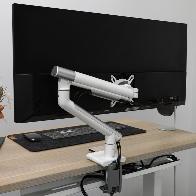 White Desky Single Slim Aluminium Monitor Arm with a subtle, slimline design, clamped to a light wood desk.