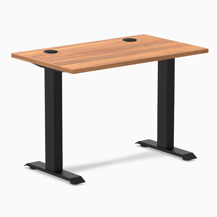 Desky Zero Mini fixed-height desk with Prime Oak top, matte black legs, and two grommets.