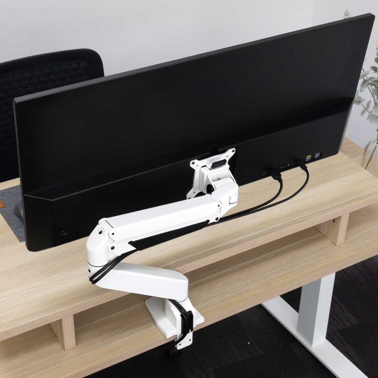 White Desky Single Monitor Arm supporting a black ultrawide monitor on a light wood desk.