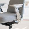 Close-up of a light grey Desky Pinnacle executive office chair with mesh back, fabric seat, and polished aluminum armrests.