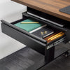 Black steel Desky under-desk drawer, open and filled with notebooks, pens, and a laptop, attached to a dark wood desk.