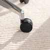 Chrome die-cast aluminum base and black caster wheel of a Desky Pinnacle office chair on a textured rug.