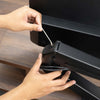 Hands adjusting a black Desky Dual Monitor Arm with integrated cable management on a wooden desk.