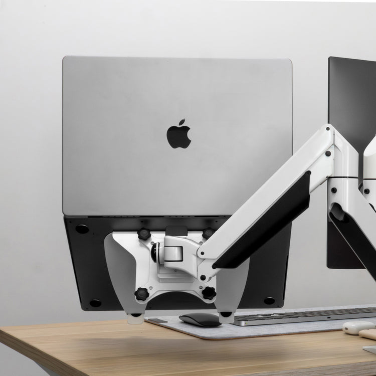 Silver laptop mounted on a black Desky universal laptop mount with a white VESA arm.
