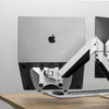 Silver laptop mounted on a black Desky universal laptop mount with a white VESA arm.