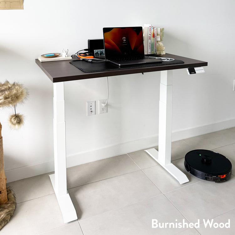 Desky Dual Mini sit-stand desk with burnished wood top and white frame, set up with a laptop.