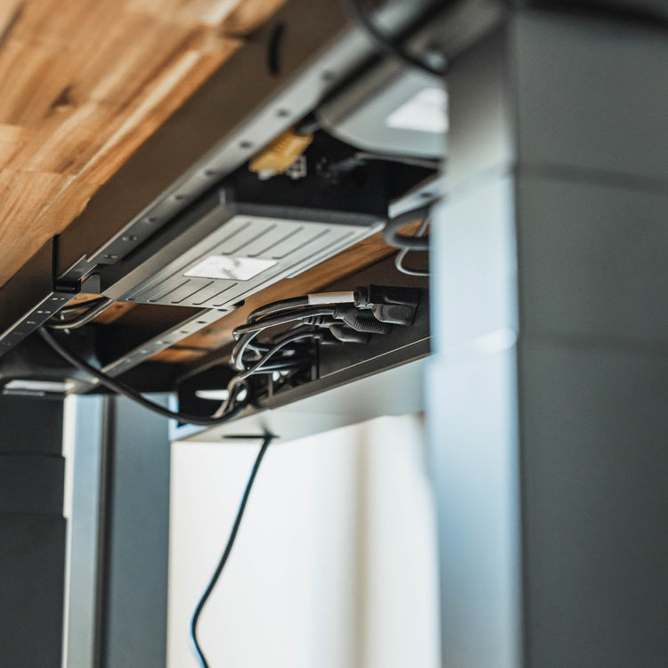 Desky Integrated Cable & Power Channel in matte black, mounted under a wooden desk, neatly organizing cables and power outlets.