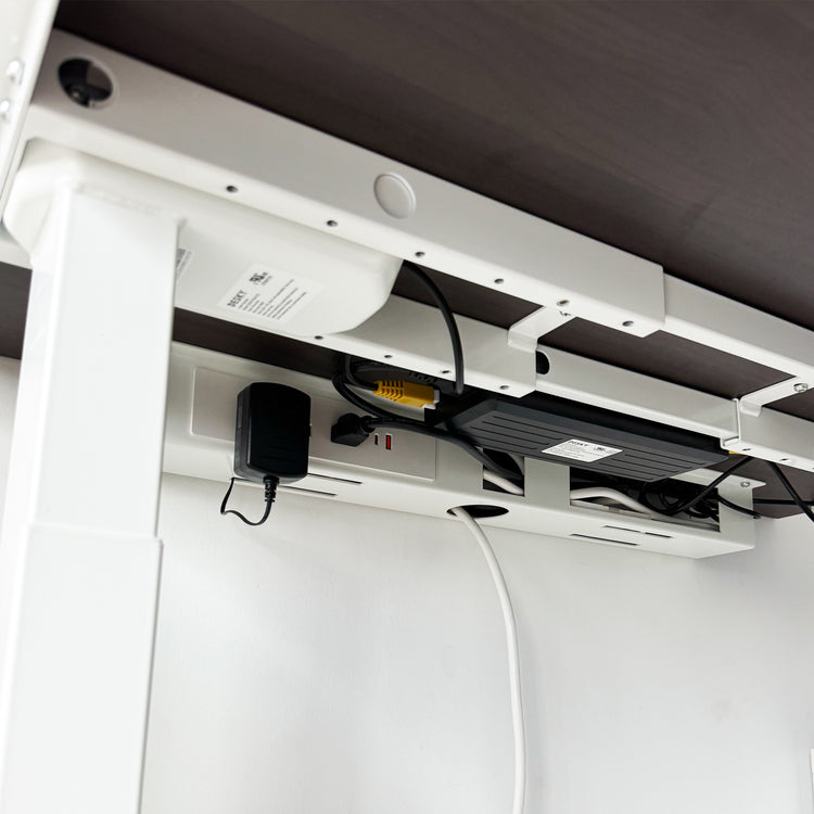 White Desky Mini Cable & Power Tray, made of powder-coated steel, neatly organizing cables under a dark desk.