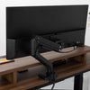Black Desky Heavy Duty Ultrawide Monitor Arm securely holding a large black monitor on a dark wood desk.