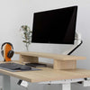 White Desky Single Monitor Arm holding a black Philips monitor on a light wood desk with a matching monitor riser.