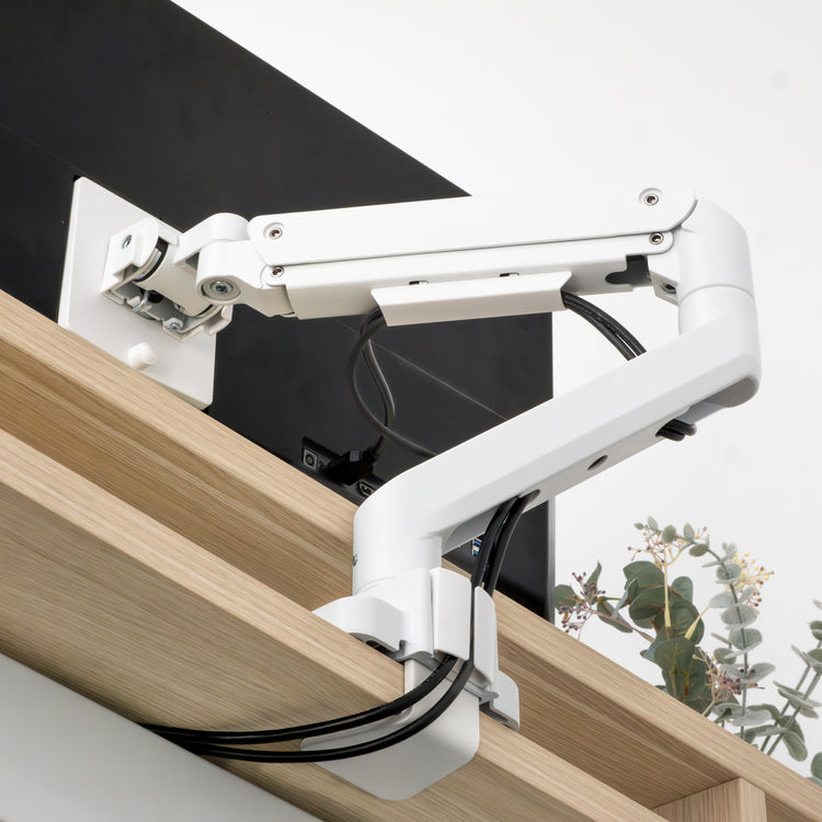White Desky Heavy Duty Ultrawide Monitor Arm clamped to a light wood desk, with cables managed.