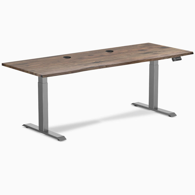 Desky Dual Laminate Sit Stand Desk with Natural Walnut top, Space Gray frame, and two grommets.