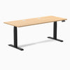 Desky Dual sit-stand desk with Sublime Teak laminate top, two grommets, and matte black frame.