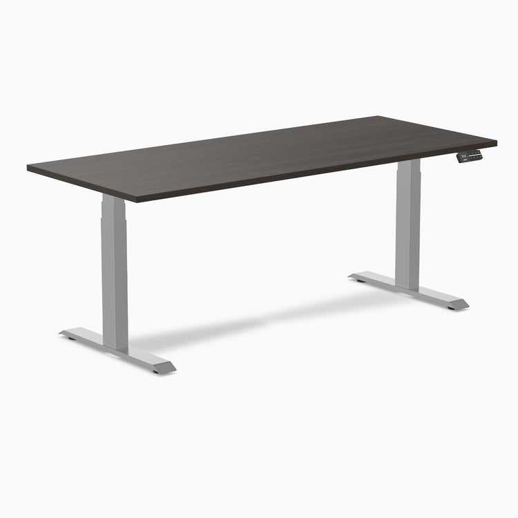 Desky Dual Laminate Sit Stand Desk with dark wood top and silver adjustable legs, featuring a control panel.
