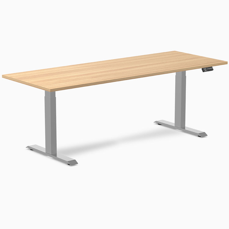 Desky Dual Custom Laminate Sit Stand Desk with light wood top and silver adjustable legs.