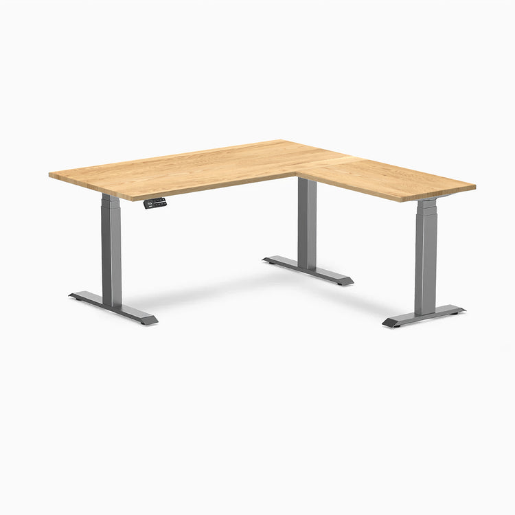 White Oak L-Shape Sit Stand Desk with Space Gray frame and control panel.