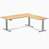White Oak L-Shape sit-stand desk with a natural hardwood top and space gray adjustable legs.
