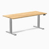 Desky Dual 72x30 inch White Oak hardwood sit-stand desk with gray legs and control panel.
