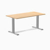 Desky Zero fixed height office desk with light wood laminate top and silver steel frame.