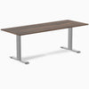 Desky Zero laminate office desk with a dark wood grain top and silver steel frame.