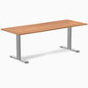 Desky Zero laminate office desk with a wood-grain top and silver steel frame, featuring a clean, minimal design.